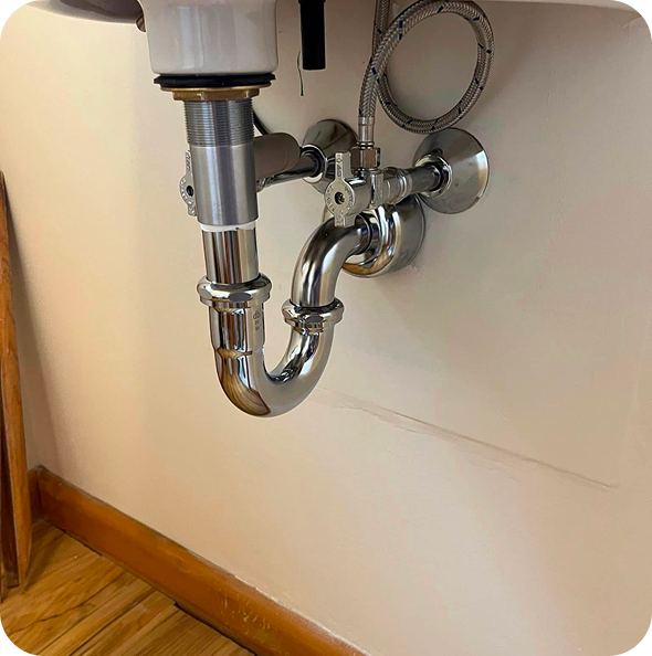 Under-sink plumbing featuring shiny metal pipes and valves, illustrating a clean and functional installation.